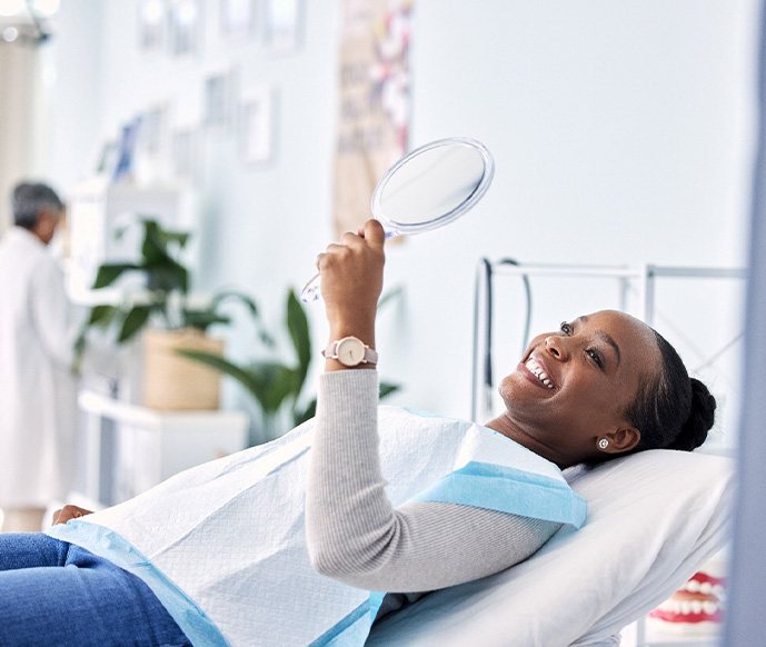 Woman smiling at reflection in handheld mirror