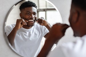 Man smiling while flossing his teeth
