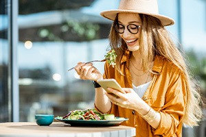 Woman smiling while looking at her phone and eating