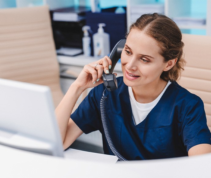 A dental assistant speaking to a patient on the phone