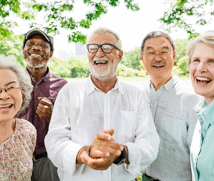 Patient in Matthews smiling confidently with friends after receiving dentures