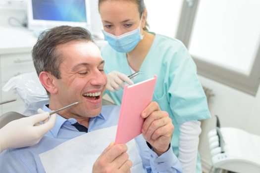 Patient admiring smile in dental mirror